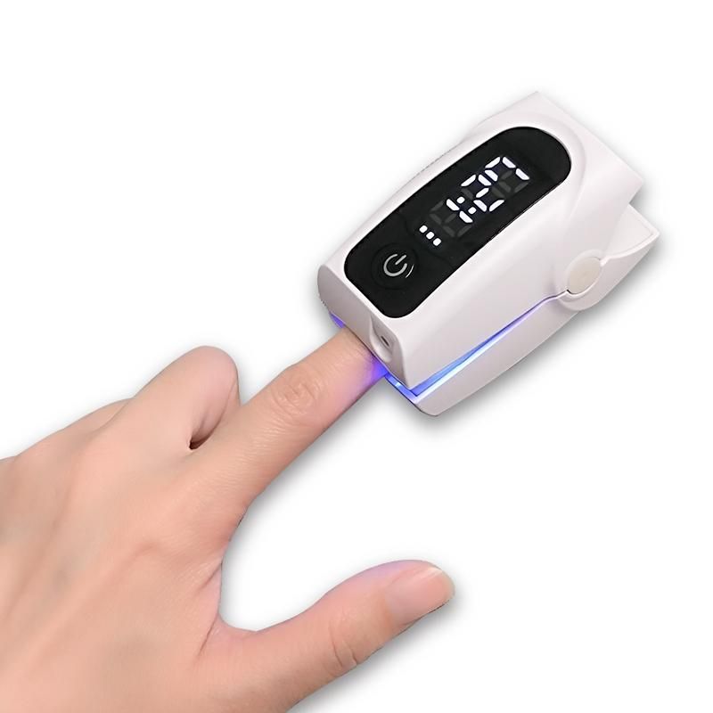 Witte digitale vingeroximeter op de vinger. Toont cijfers. Met aan/uit-knop.
