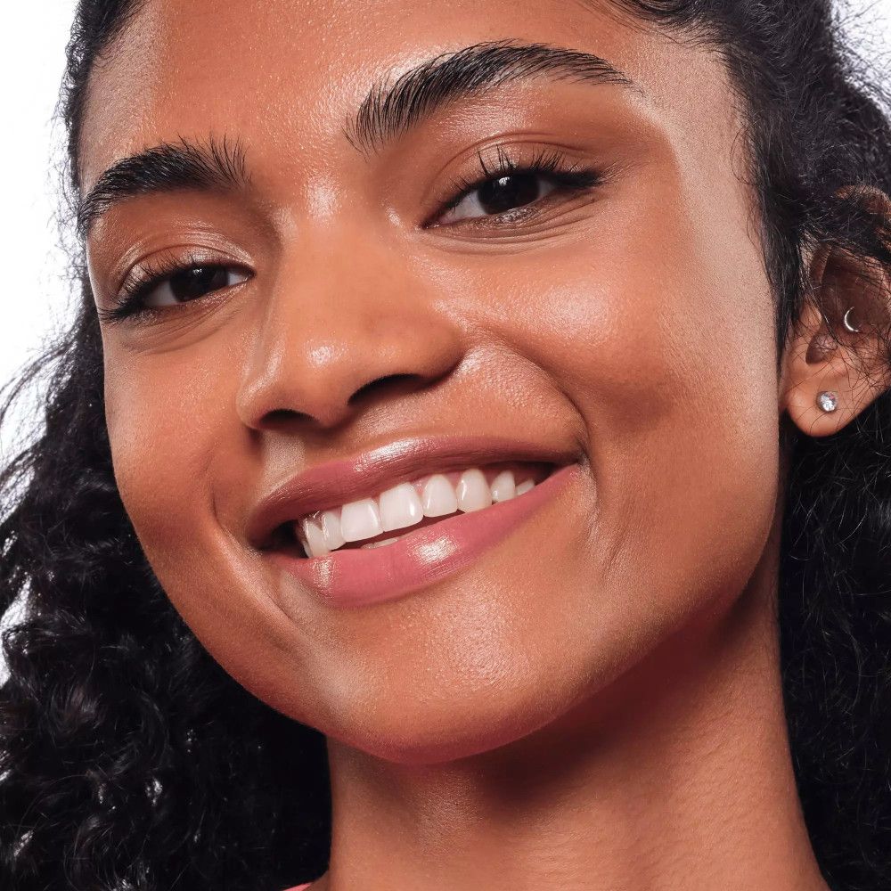 Portrait d'une femme avec du rouge à lèvres rose. Elle sourit.