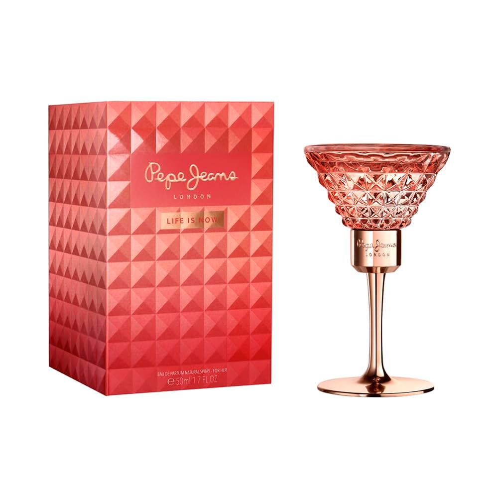 Flacon de parfum en forme de verre à martini à côté d'une boîte d'emballage rose à motif géométrique.