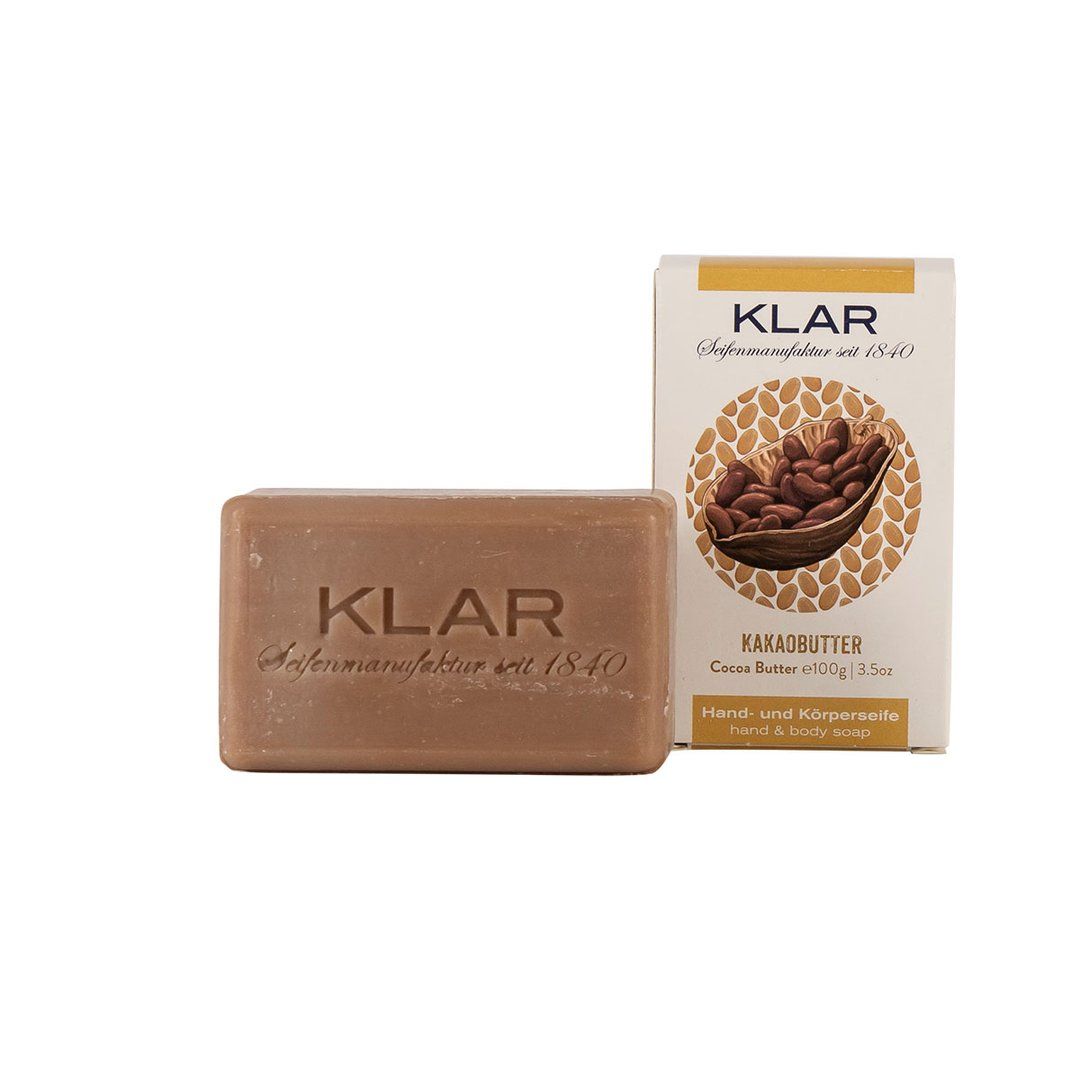 Klar-zeep en verpakking. Rechthoekige zeep met KLAR-reliëf. Verpakking met cacaobonenillustratie en opschrift cacaoboter.