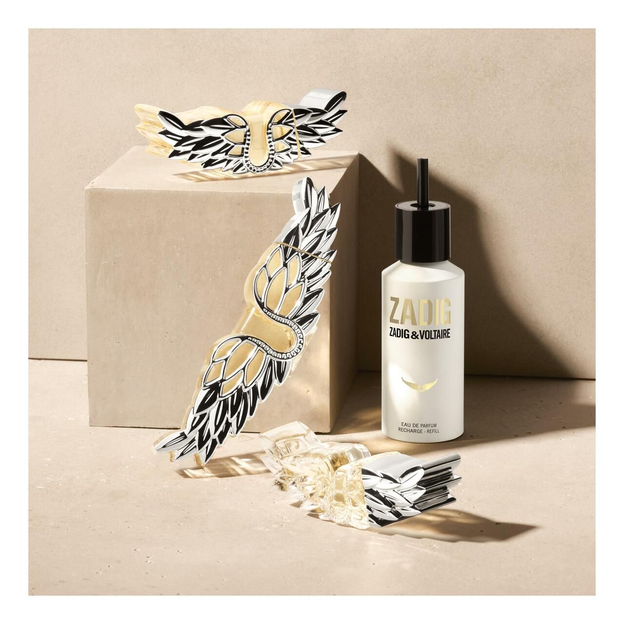 Flacon Zadig & Voltaire Zadig EDP, décorations d'ailes et cubes sur fond beige.