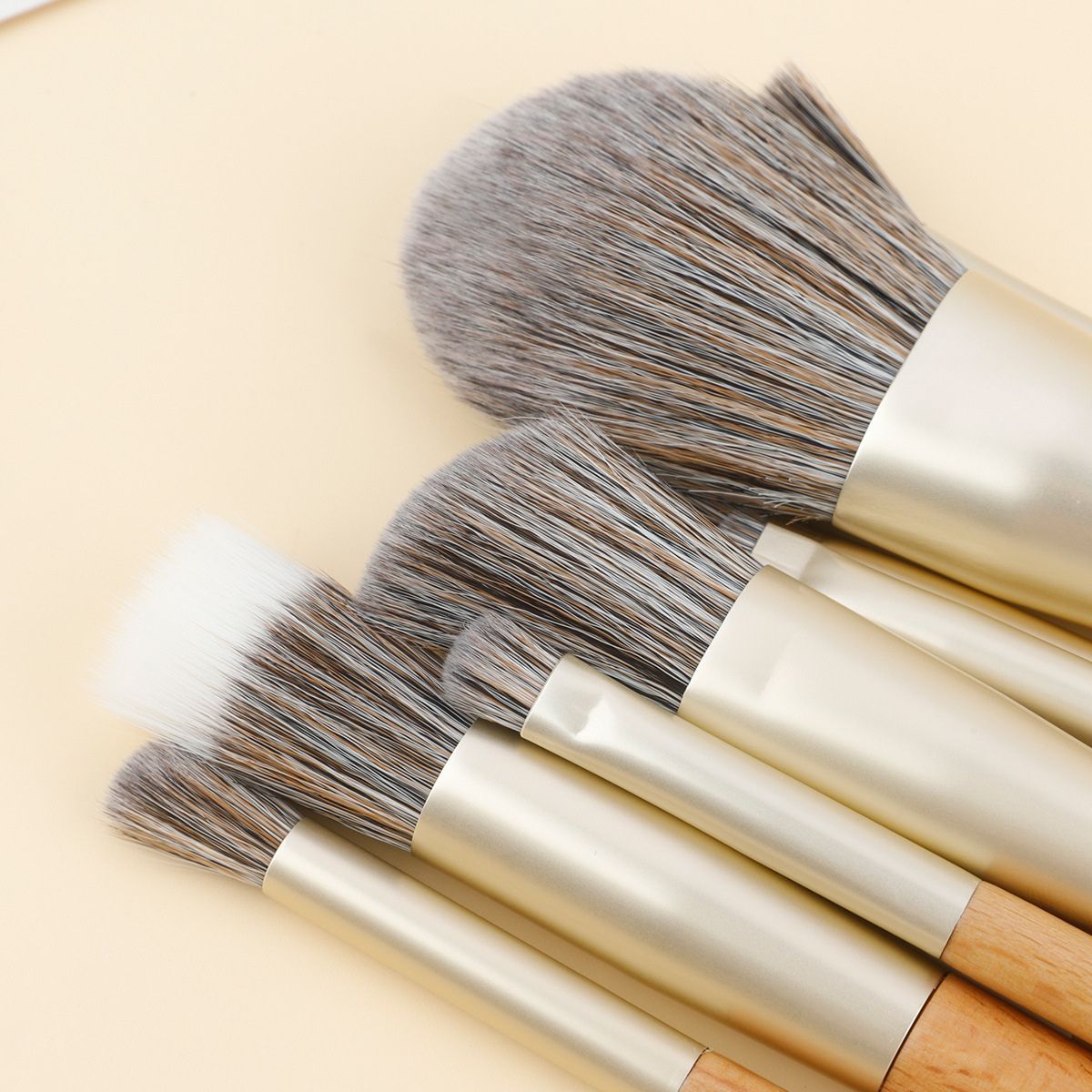 Ensemble de pinceaux de maquillage avec manches en bois et viroles dorées. Poils doux multicolores.