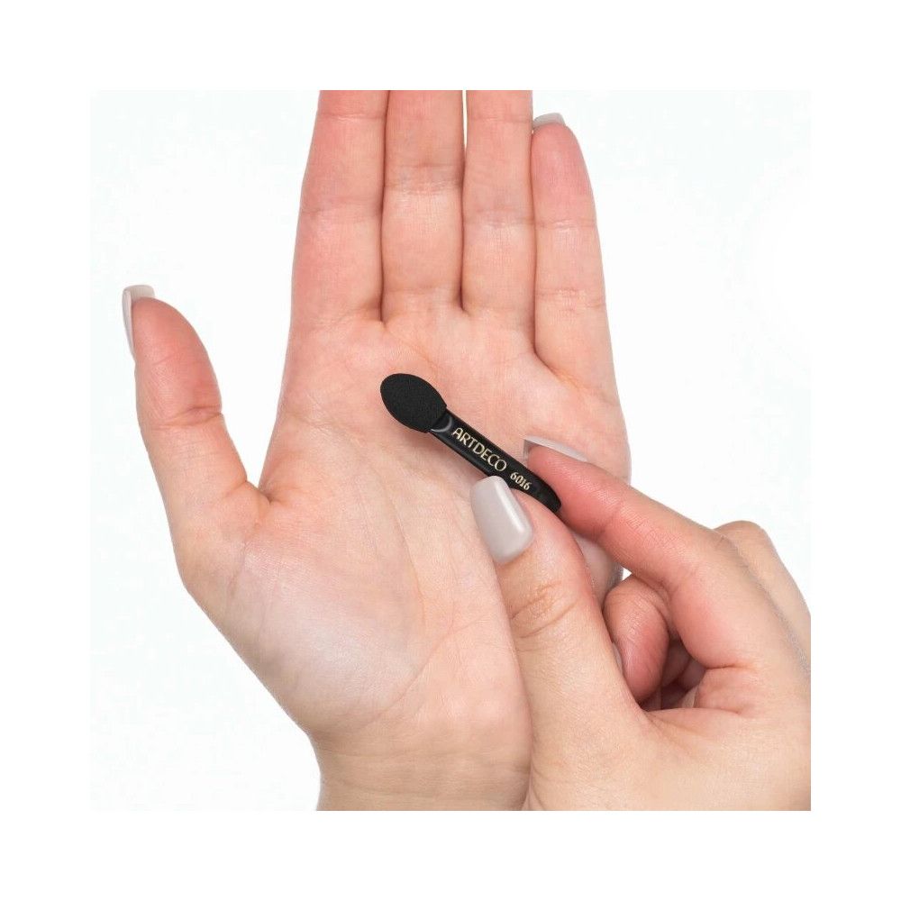 Applicateur en mousse synthétique noir, tenu dans une main. Le manche porte la mention ARTDECO 6016.