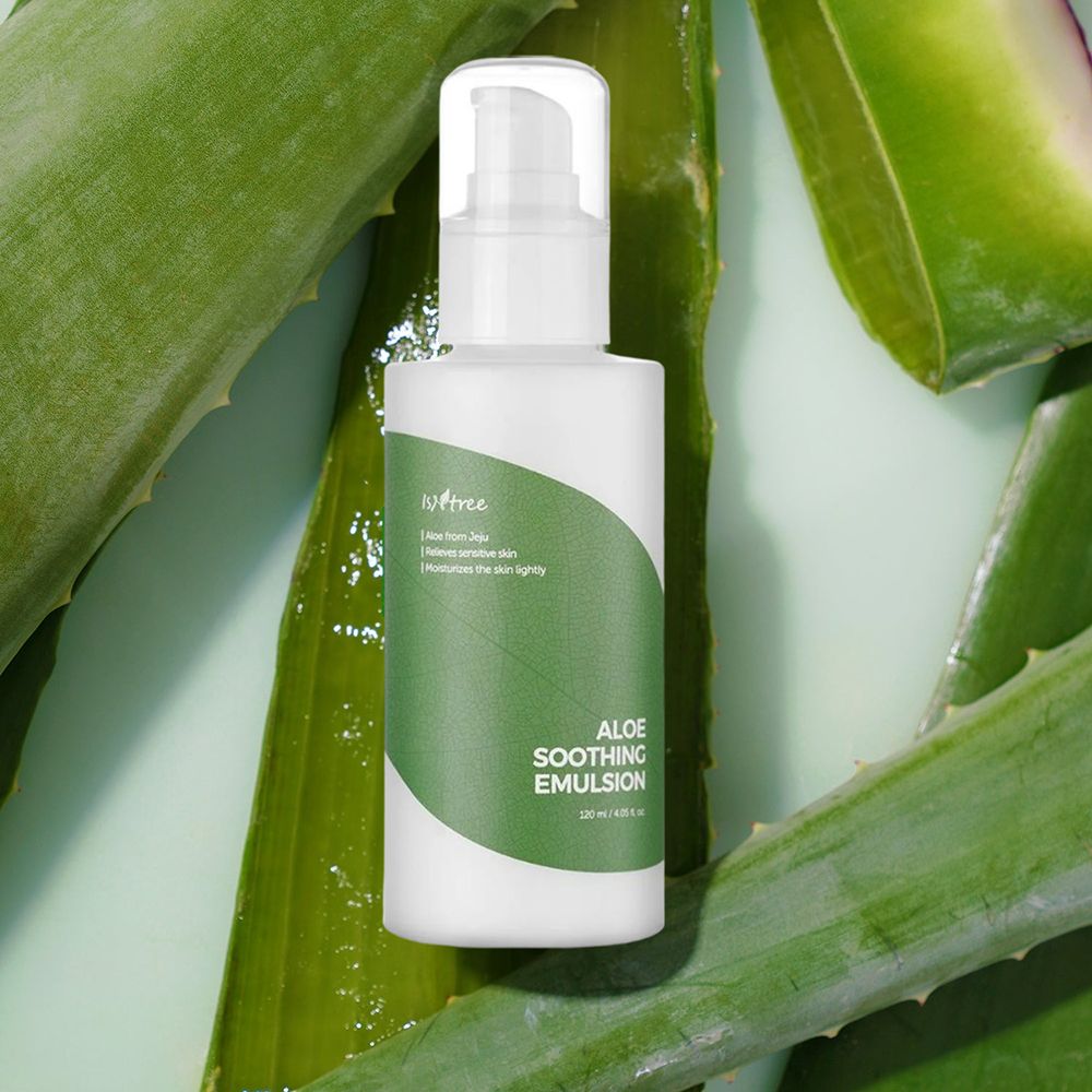 Witte fles met groen etiket. Tekst: Aloe Soothing Emulsion. Omringd door aloë vera bladeren.
