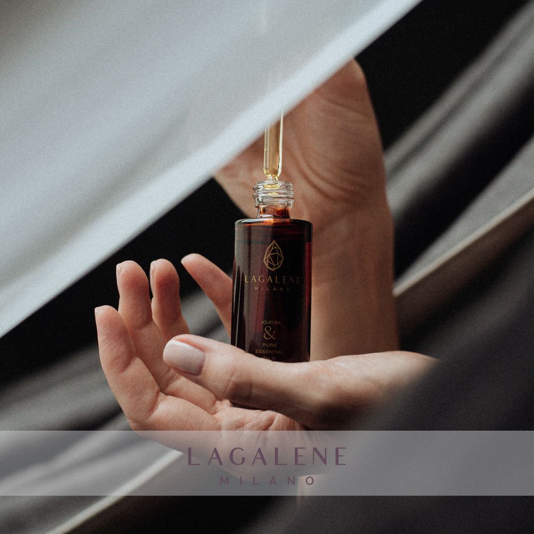 Bruine glazen fles van Lagalene Milano met een gouden pipet, vastgehouden in een hand. Op het etiket staat "Jojoba & Pure Essential Oils".