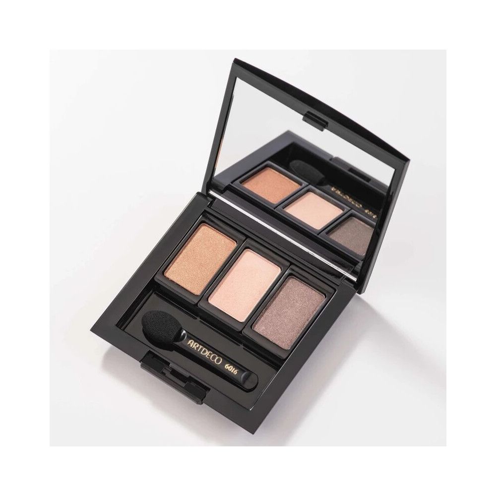 Palette de maquillage noire avec miroir et trois fards à paupières. Un applicateur est à côté. Le manche porte ARTDECO 6016.