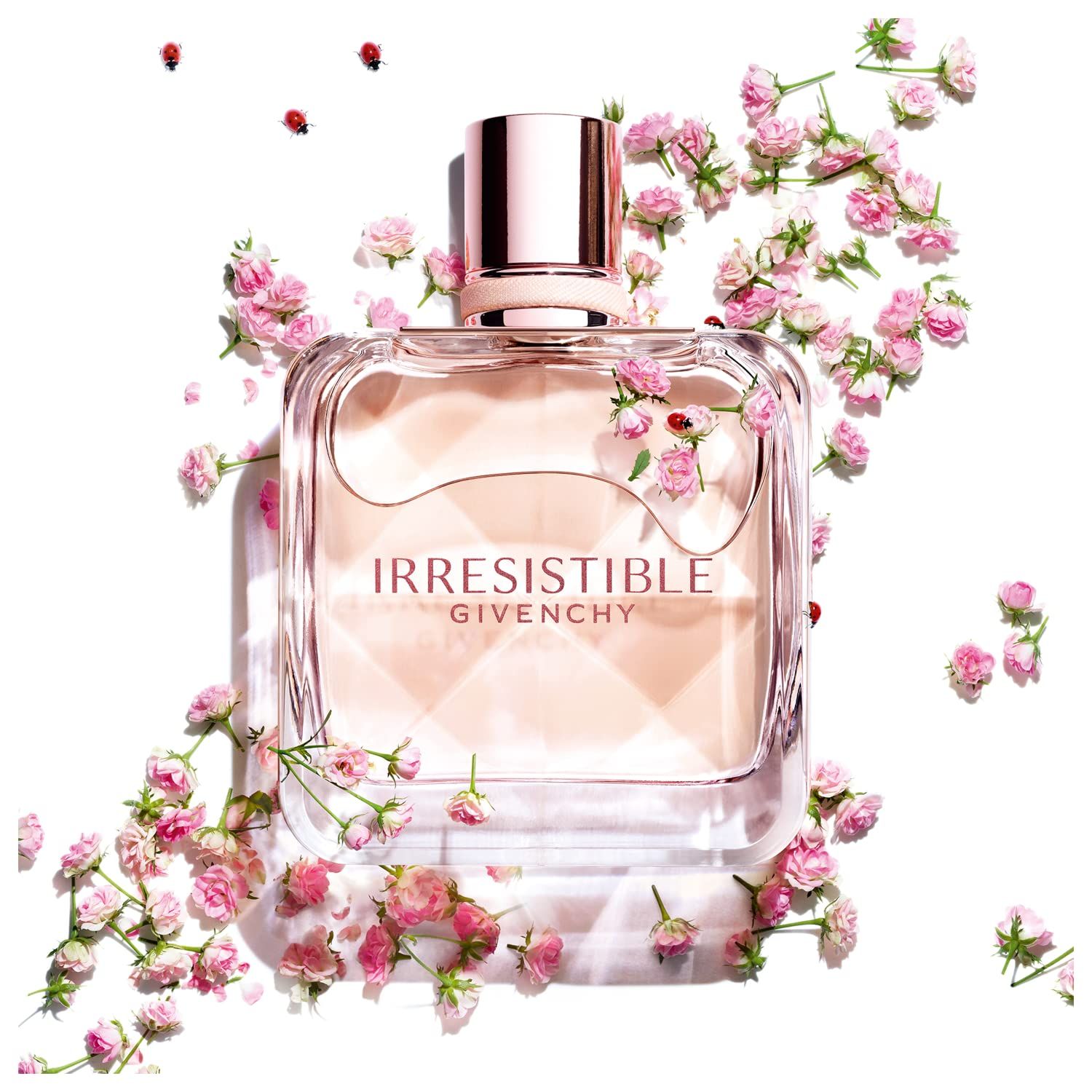 Parfumflesje Irresistible Givenchy omringd door kleine roze bloemen. Vierkante vorm, roségouden dop.