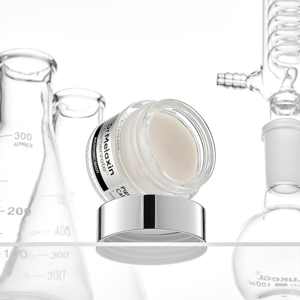 Een open pot met witte crème staat op de deksel, omringd door laboratoriumapparatuur.