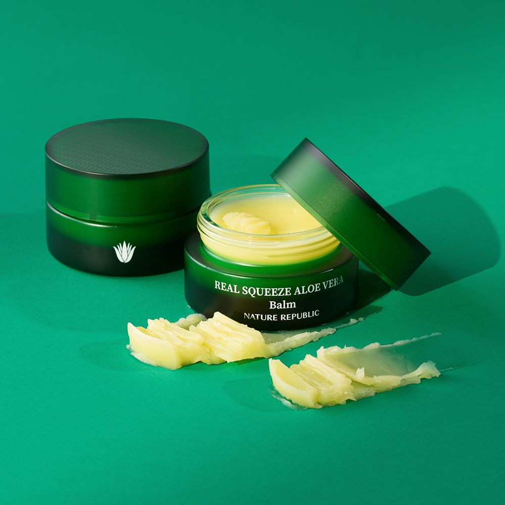 Twee groene potten met gele balsem en strepen. Opschrift: Real Squeeze Aloe Vera Balm.