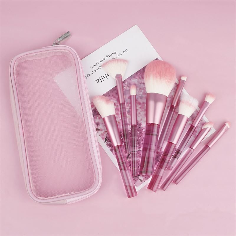 Ensemble de pinceaux de maquillage roses avec étui. Pinceaux avec manches transparents et poils roses. Sur fond rose.