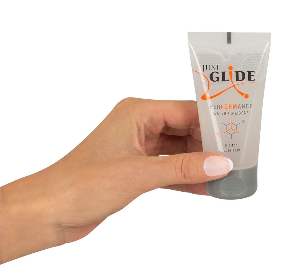 Hand houdt Just Glide Performance glijmiddel tube vast, Water + Siliconen.