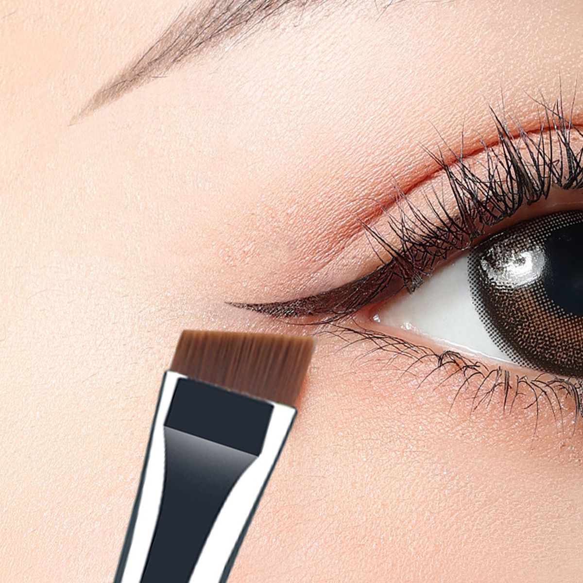 Een schuine oogmake-up kwast wordt op een oog aangebracht om eyeliner aan te brengen.