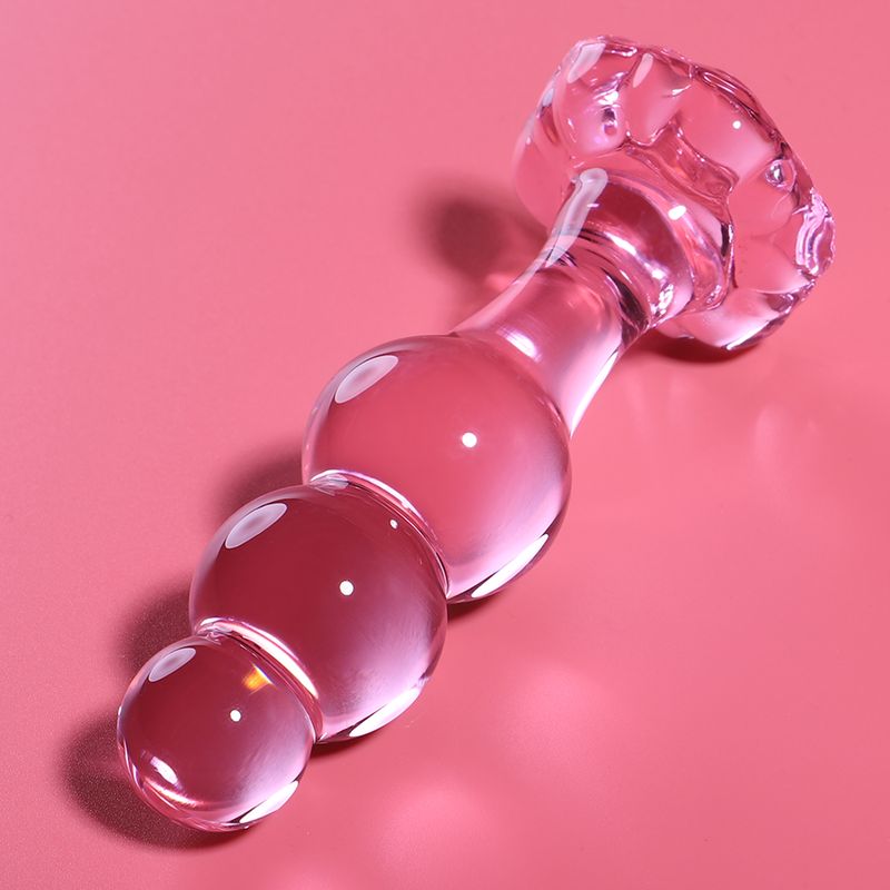 Een transparante, roze glazen butt plug met een bolvormig uiteinde en een bredere grip.