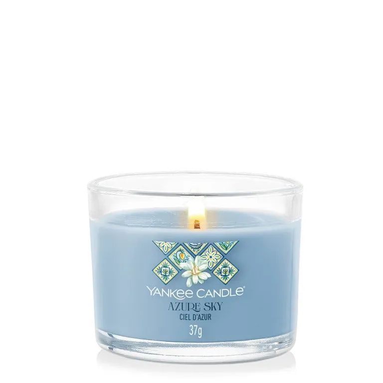 Bougie bleu clair dans un verre. Inscription: Yankee Candle Azure Sky, 37g. Flamme allumée.