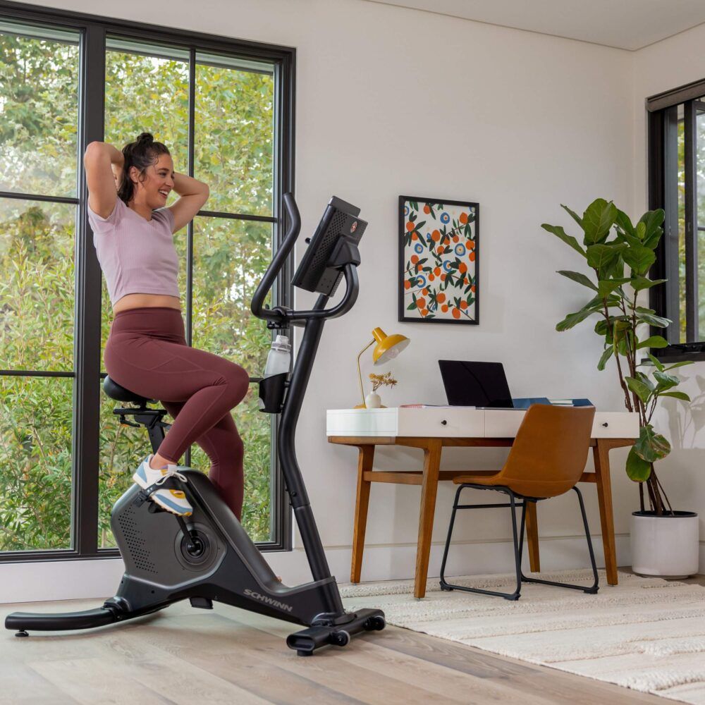 Femme faisant de l'exercice sur un vélo d'appartement. Schwinn Fitness 590U. Bouteille d'eau.