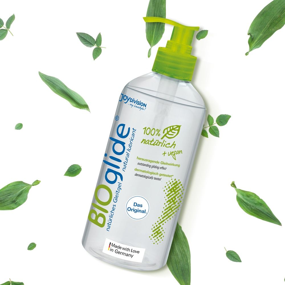 Fles BIOglide glijmiddel met pompdos op witte achtergrond met bladeren.