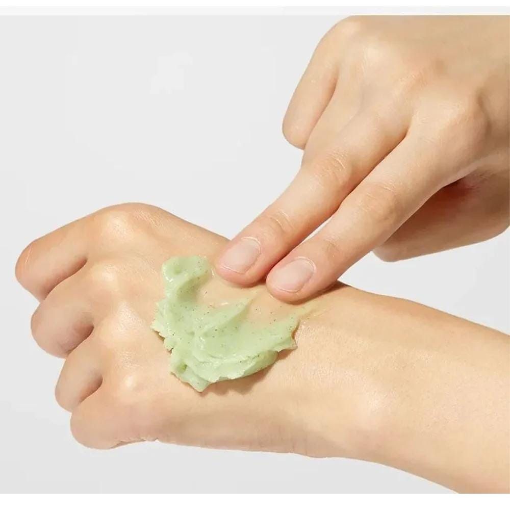Handen met groenachtige balsem. Eén hand raakt de balsem op de andere hand aan. Lichte huid, lichte achtergrond.