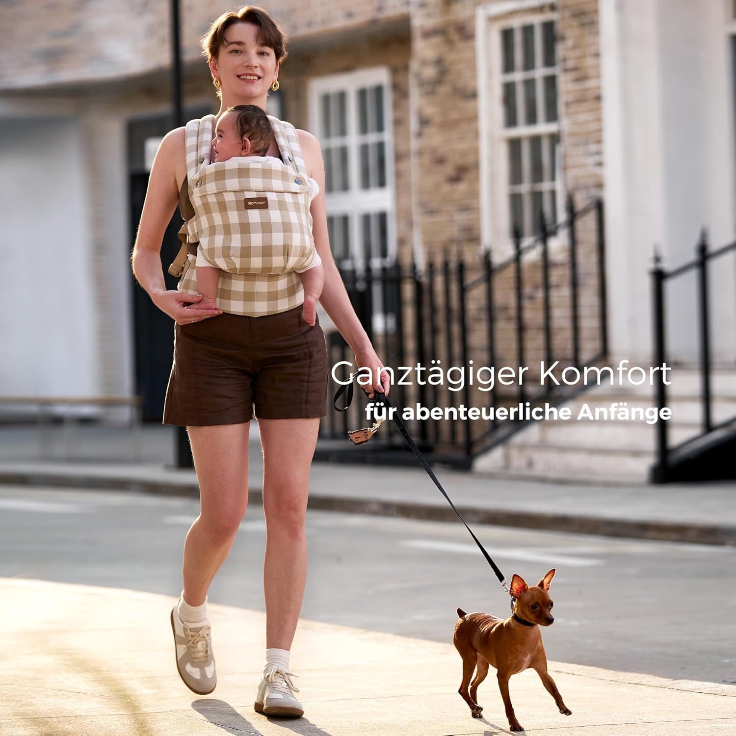 Vrouw met baby in babydrager met leisteen-ruitpatroon, wandelend. Tekst: Comfort de hele dag.