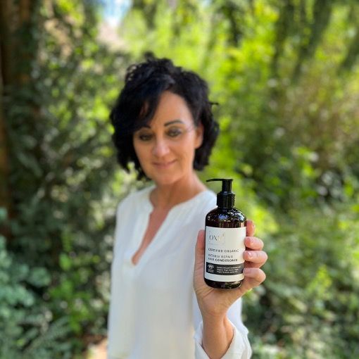 Femme tenant un flacon de produit. Texte: INTENSE REPAIR HAIR CONDITIONER. Flacon brun avec pompe noire.