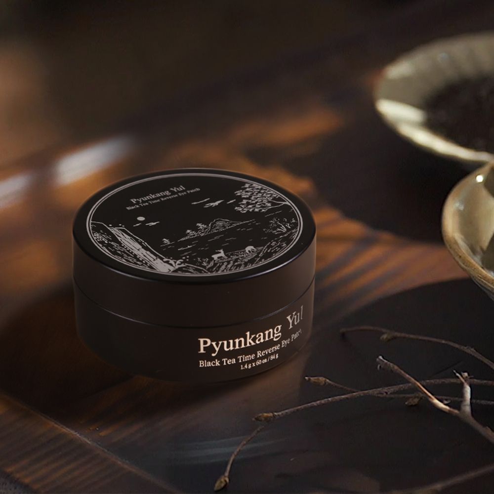 Pot noir avec patchs oculaires sur une table en bois, près de branches et de bols.