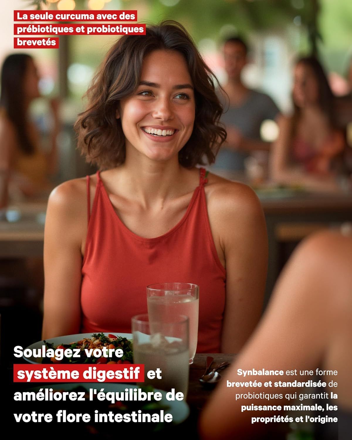 Femme souriante dans un restaurant, vêtue de rouge, verres d'eau sur la table.