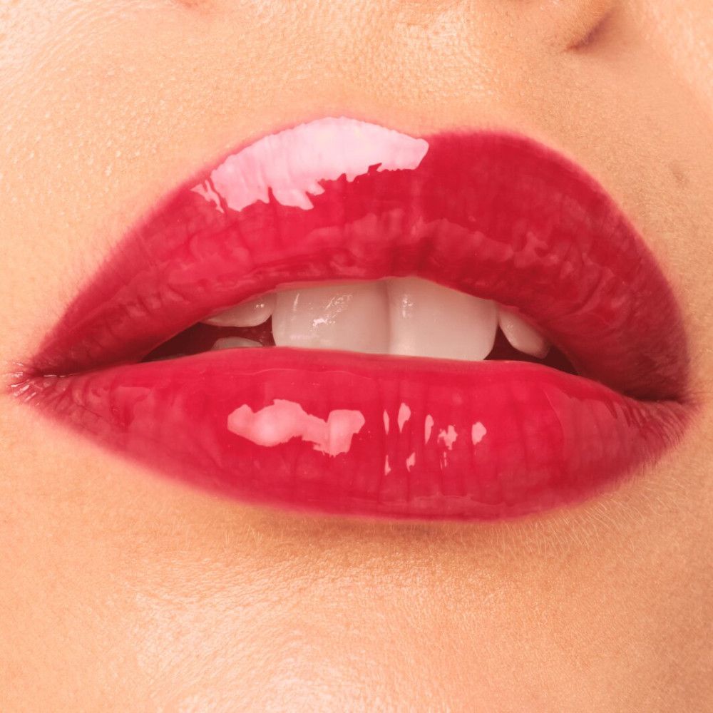 Close-up van lippen met rode lipgloss. Glanzende finish. Zichtbare tanden.