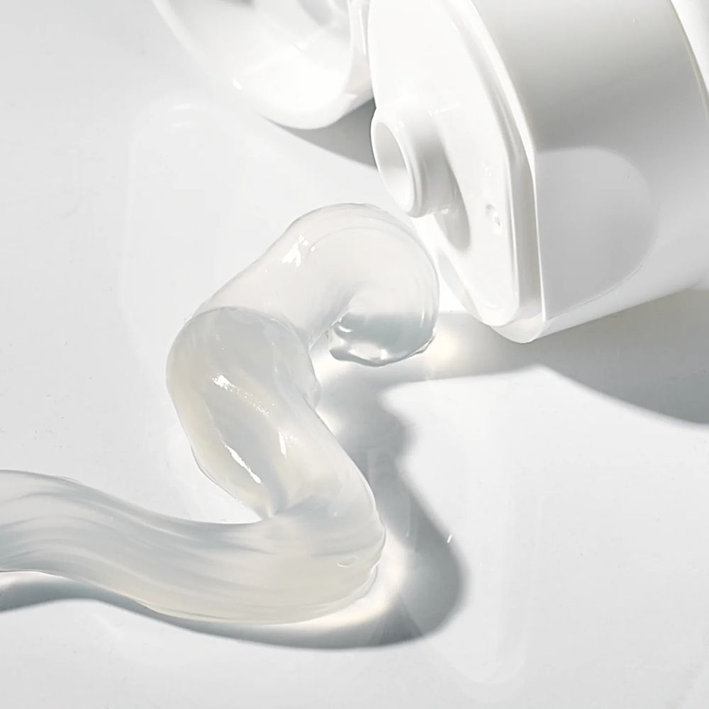 Close-up van tandpasta die uit een tube komt. De tandpasta is transparant en heeft een golvende vorm.