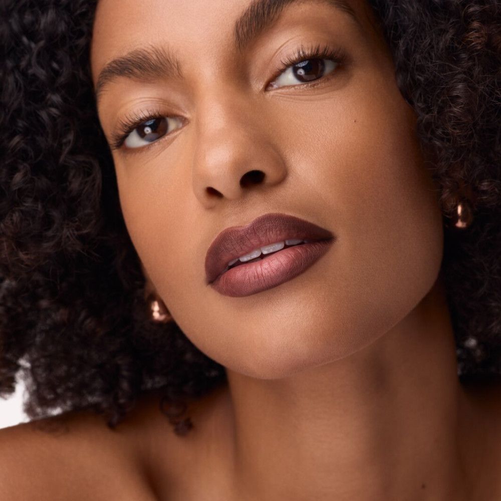 Portrait d'une femme avec des lèvres maquillées en marron. Regarde directement la caméra.