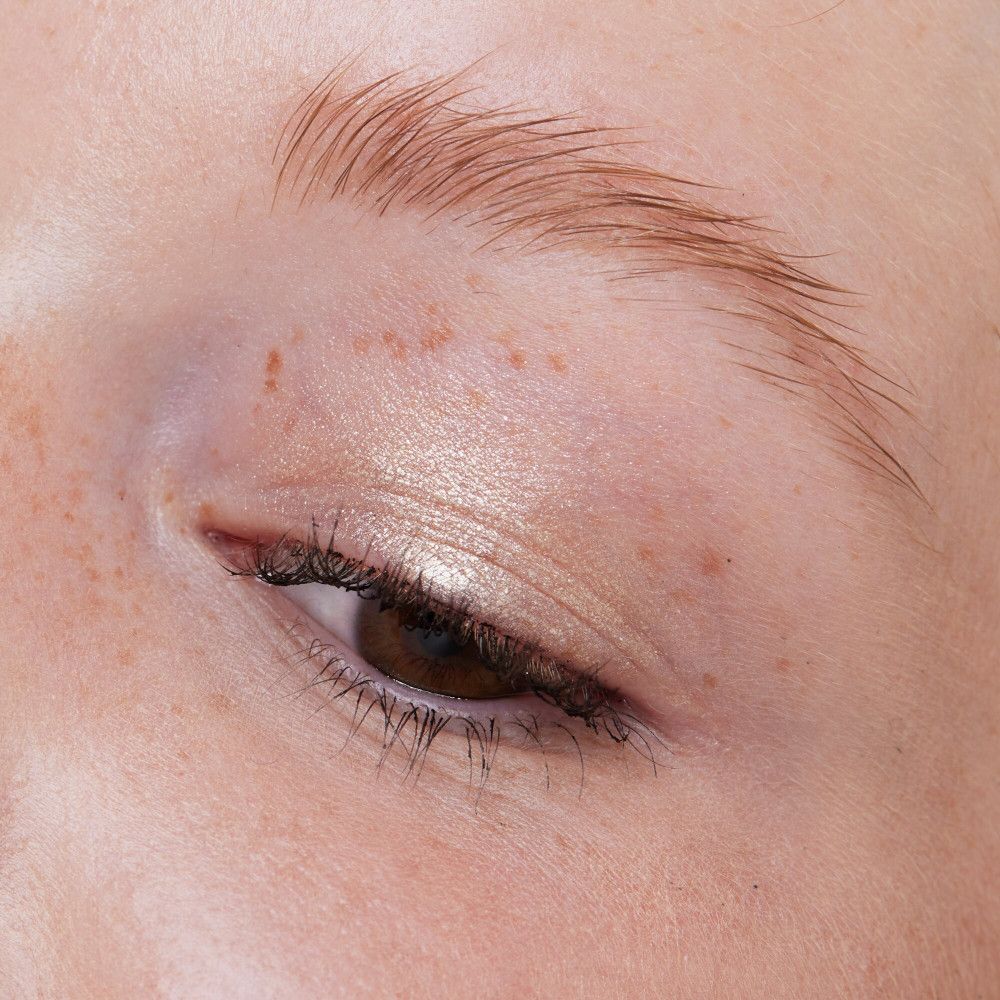 Oog met oogschaduw. Lichte, glanzende kleur op het ooglid. Bruine ogen, lichte huid.