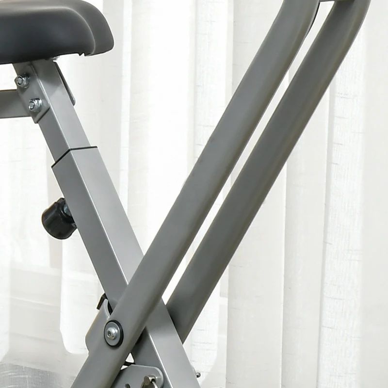 Grijze metalen staven van een hometrainer. Witte gordijn op de achtergrond.