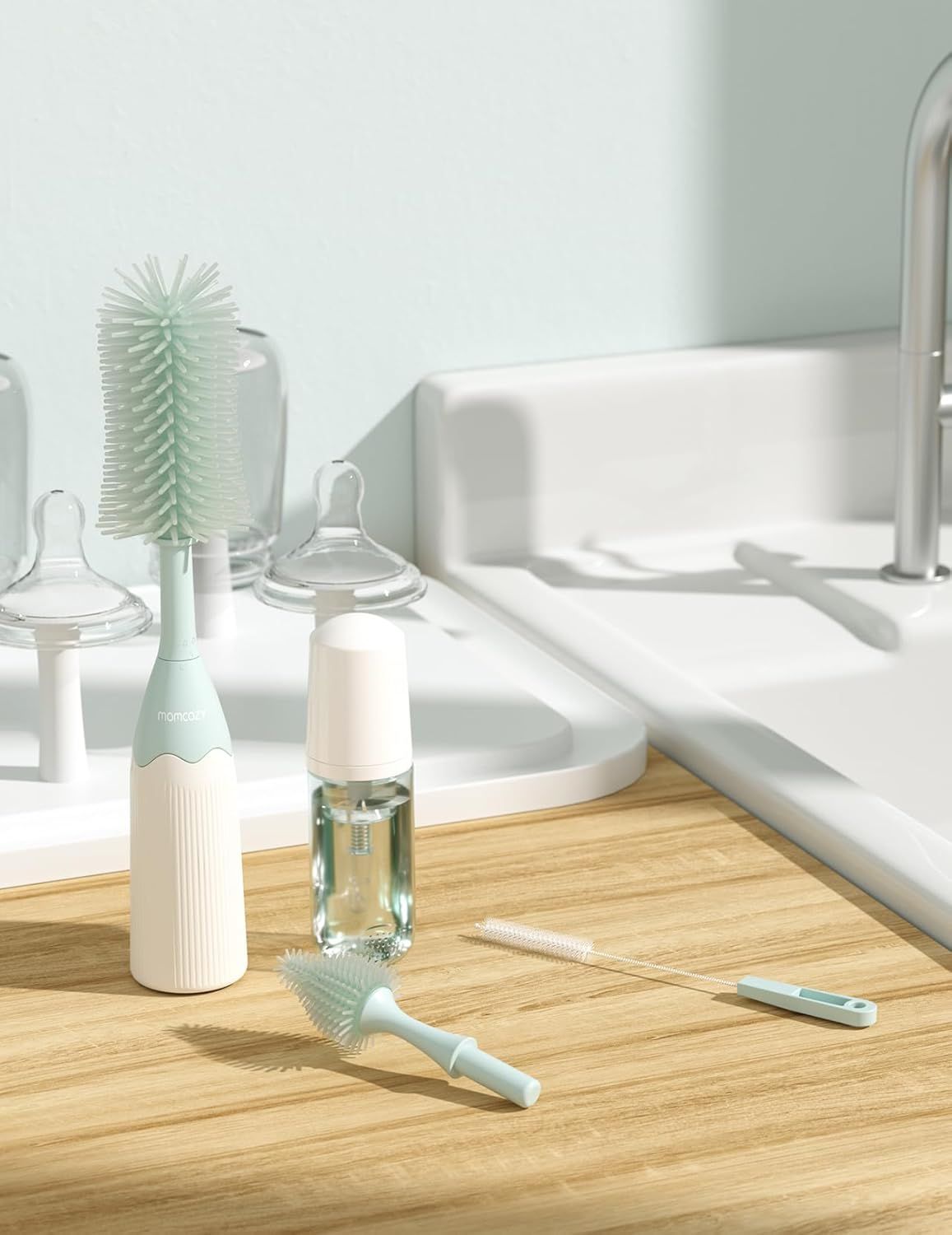Brosse à biberon Momcozy, petite tête de brosse et liquide de nettoyage sur un plan de travail.