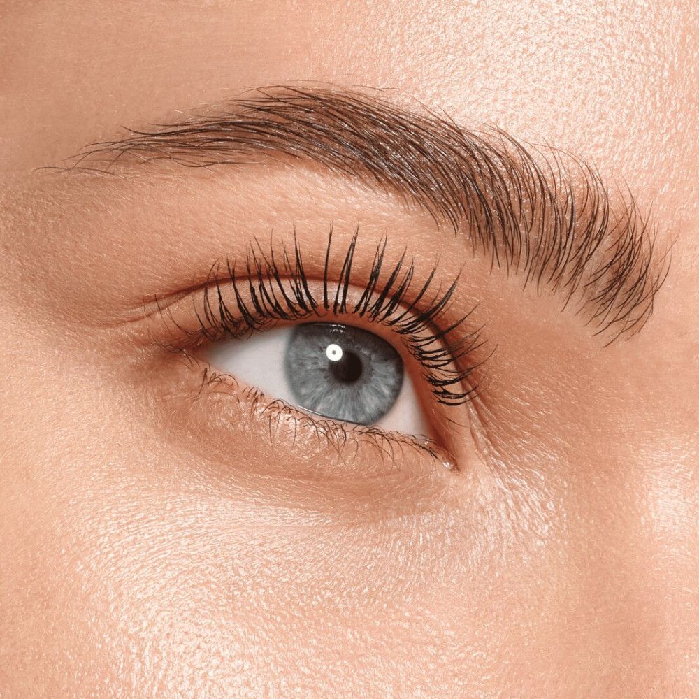 Gros plan d'un œil bleu avec de longs cils maquillés. Sourcils bruns.