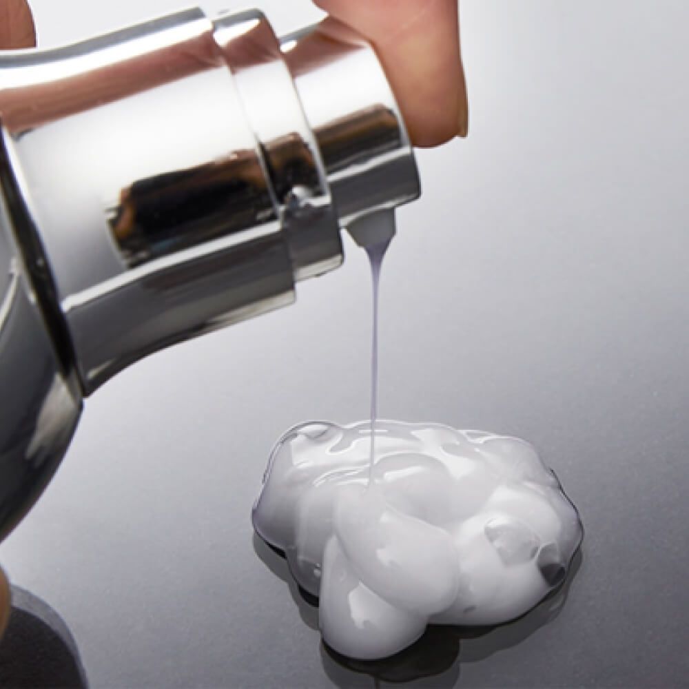 Pompe argentée délivrant un liquide blanc et crémeux.
