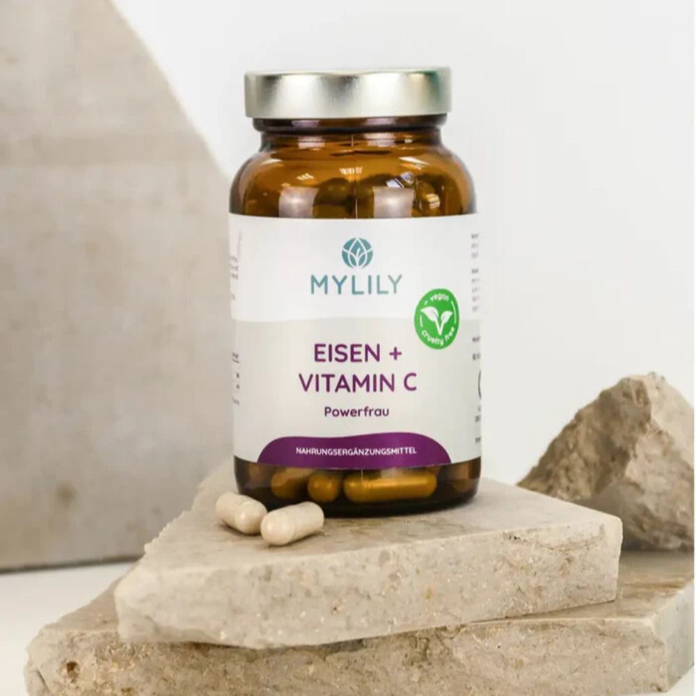 Bruine fles met capsules op steen. Opschrift: MYLILY, IJzer + Vitamine C, Powerfrau. Voedingssupplement.