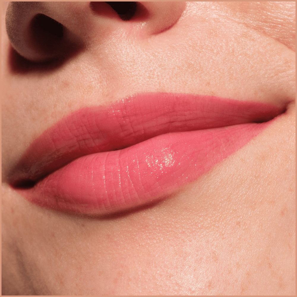 Gros plan sur les lèvres. Les lèvres sont remplies d'un remplisseur de lèvres rose.
