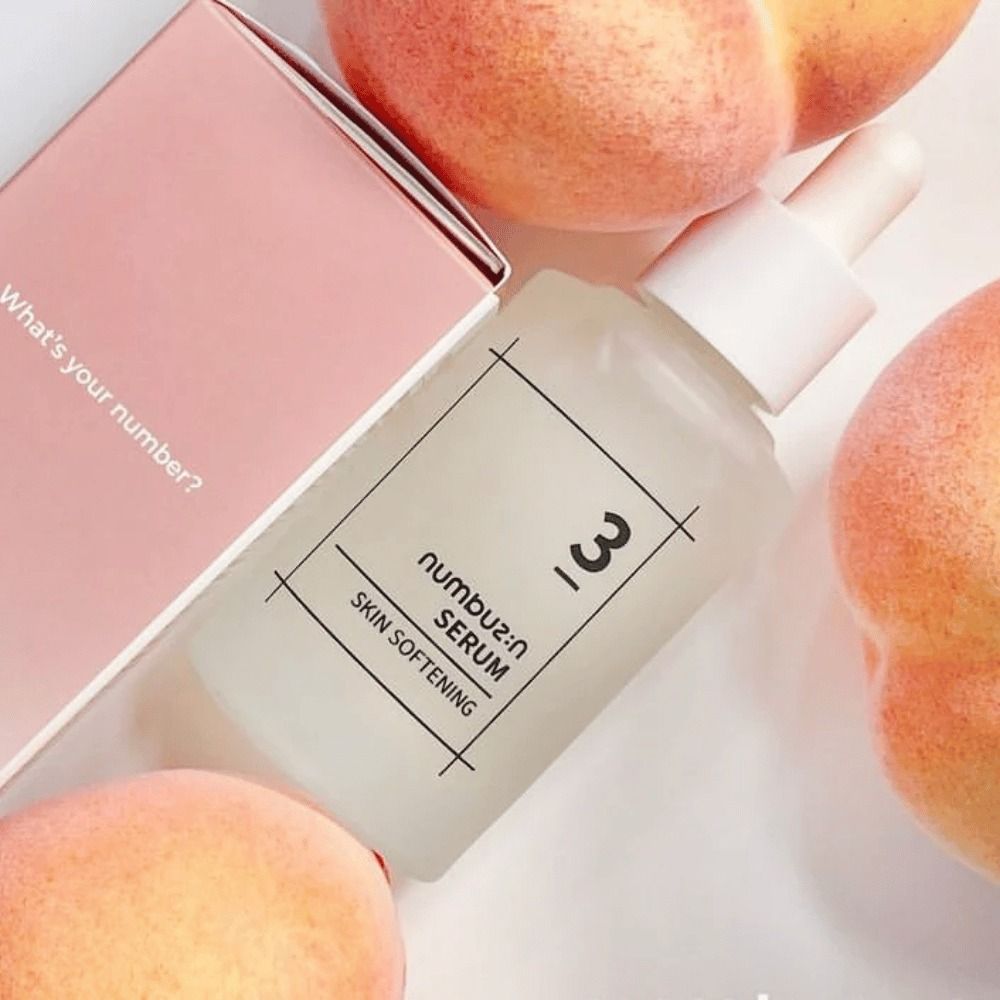 Serumfles met perziken en verpakking. Opschrift: 3, numbu:z:n SERUM SKIN SOFTENING. Verpakking met tekst.
