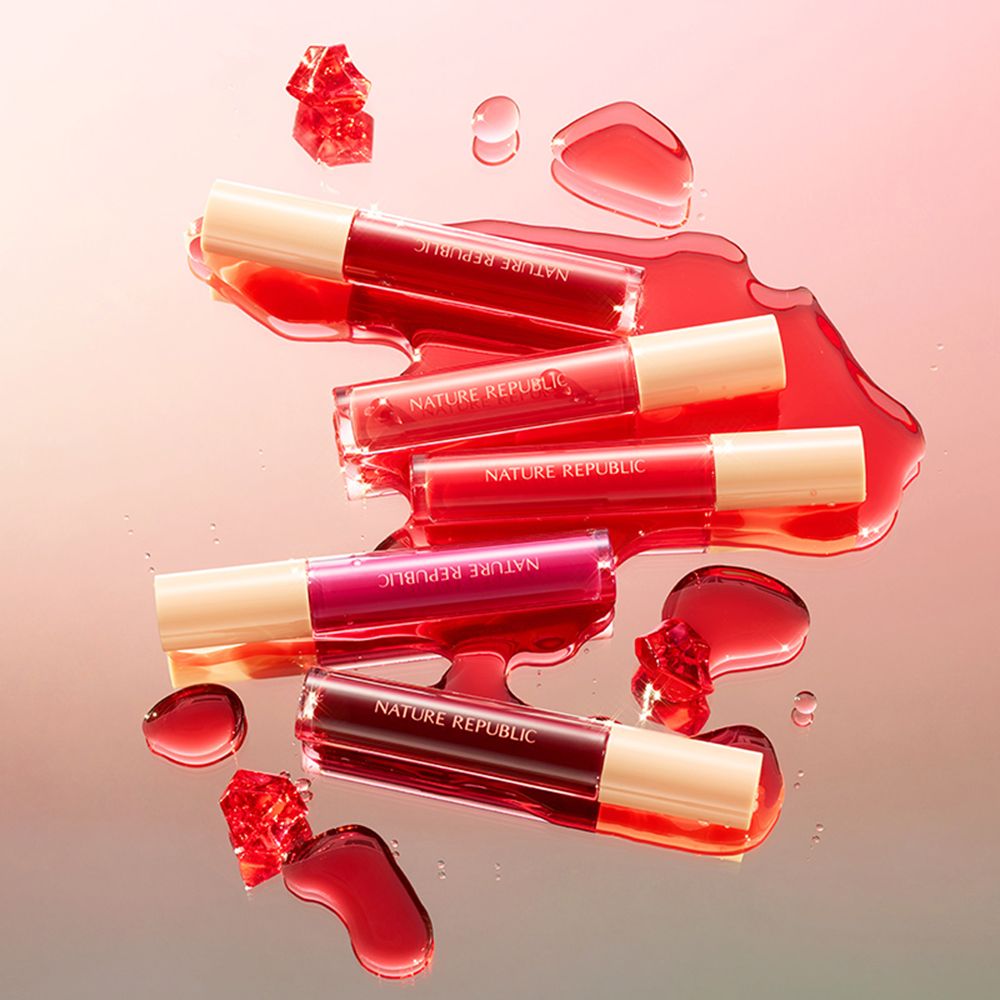 Plusieurs tubes de gloss de différentes nuances de rose. Ils sont dans un liquide rouge. NATURE REPUBLIC est écrit sur les tubes.