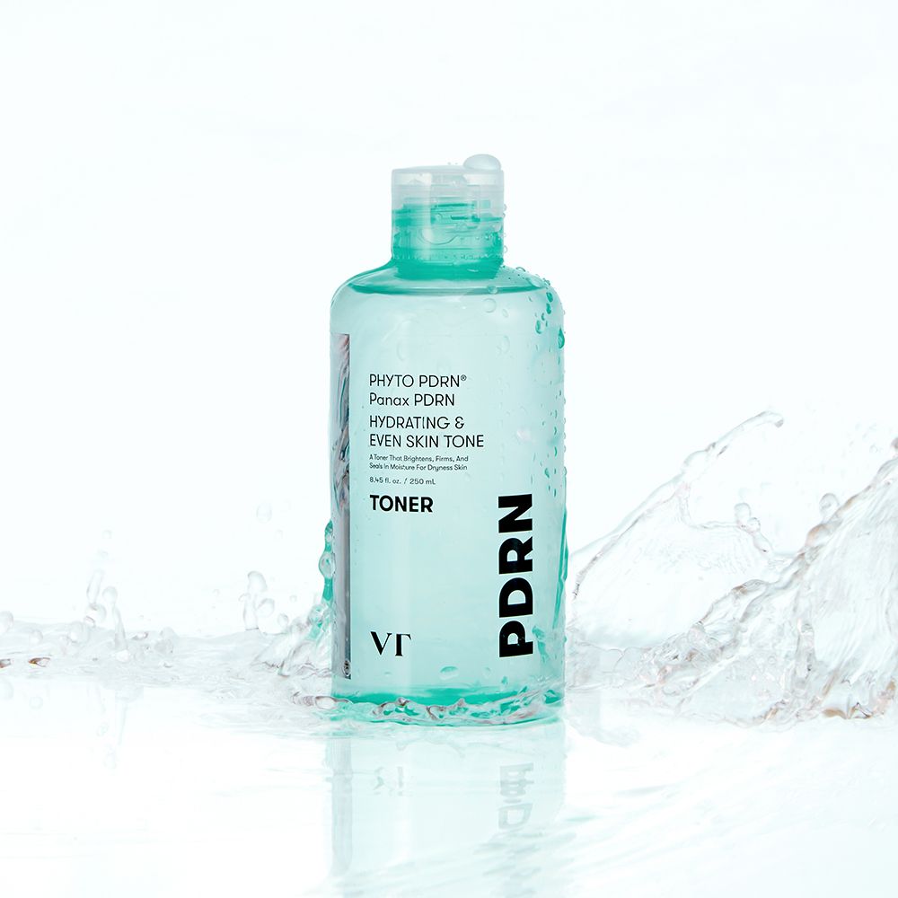 Bouteille verte de toner VT COSMETICS PHYTO PDRN. De l'eau éclabousse autour de la bouteille.