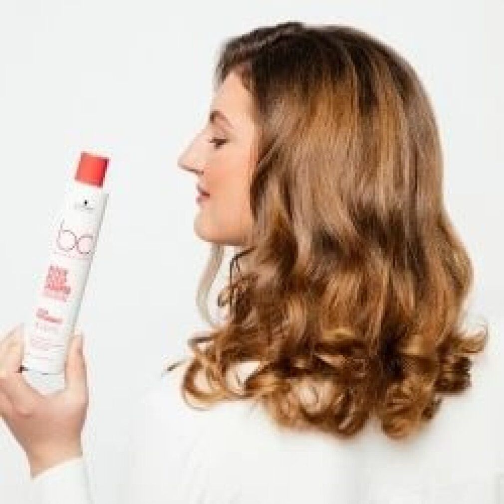 Vrouw houdt fles vast. Opschrift: bc Bonacure Repair Rescue Conditioner Arginine. Vrouw met golvend haar, in profiel.