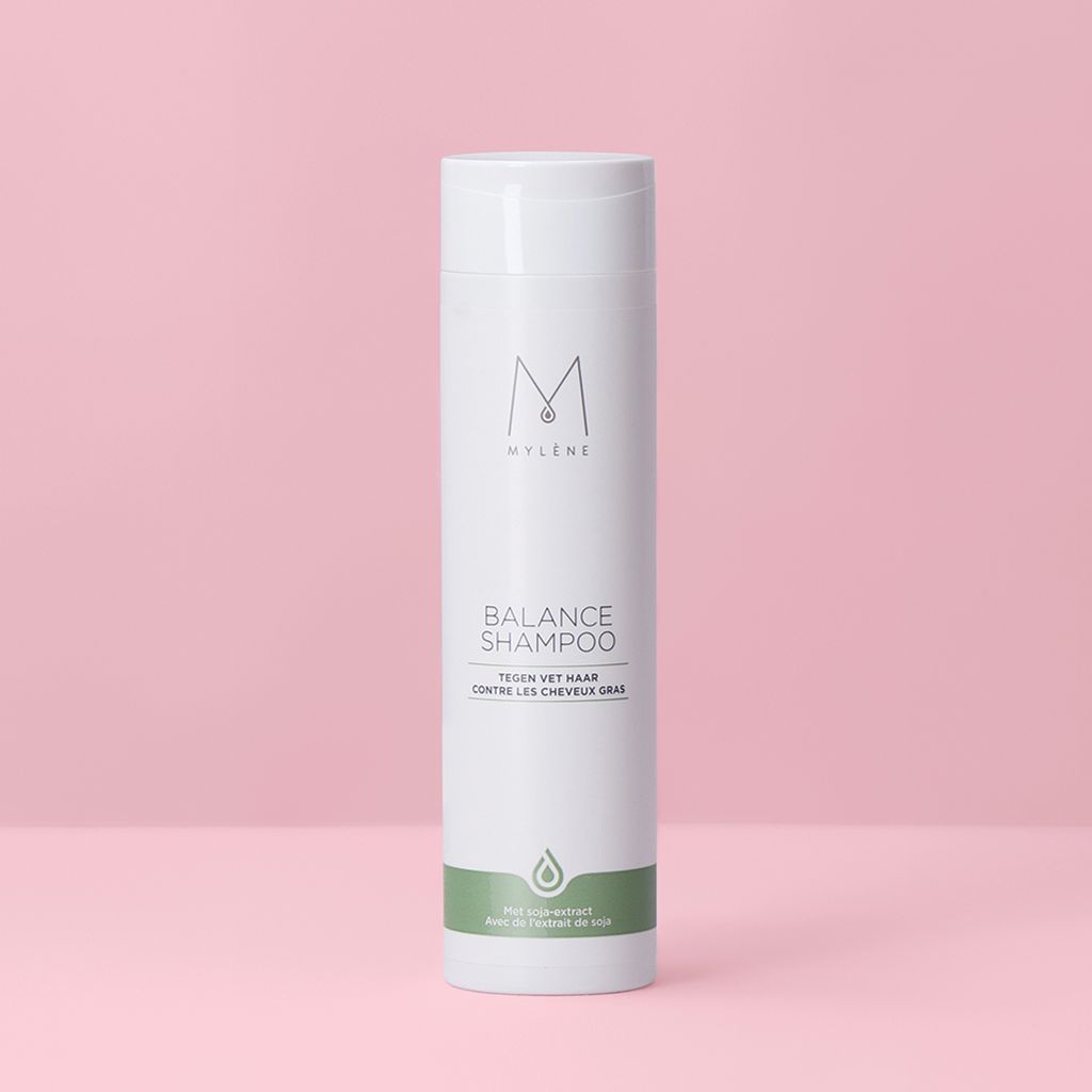 Witte shampoo met groene streep. Tekst: Balance Shampoo, tegen vet haar. Logo: M. Fles voor roze achtergrond.