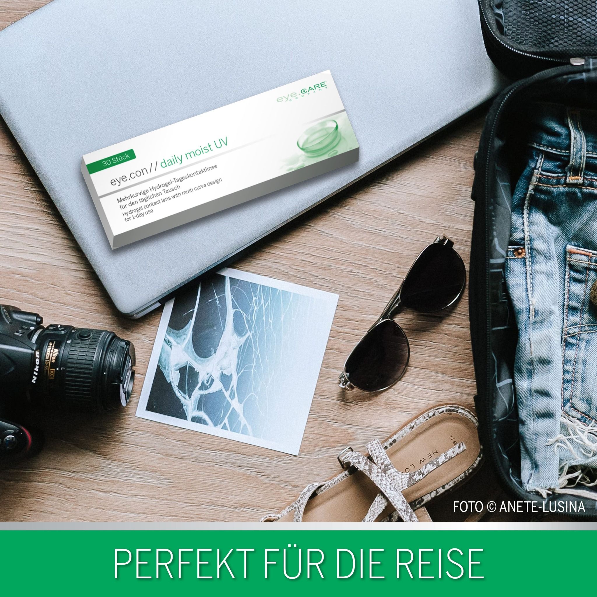 Verpakking met contactlenzen op een laptop, naast reisartikelen.