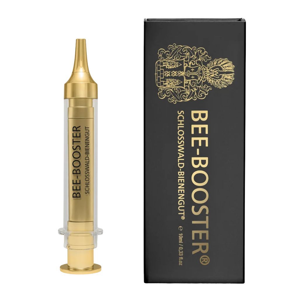 Gouden spuit en zwarte verpakking met gouden tekst. Opschrift: BEE-BOOSTER® en Schloßwald-Bienengut®.
