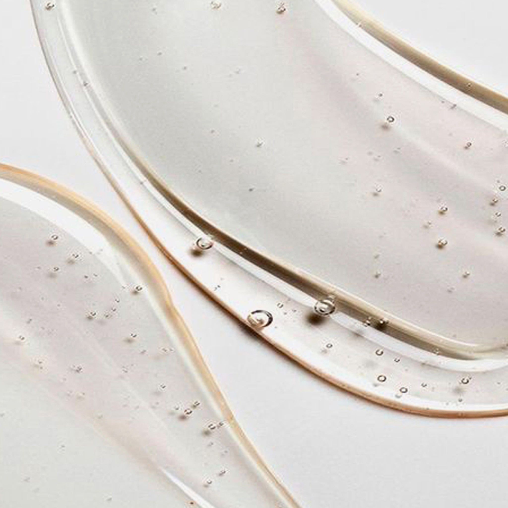 Gros plan de gel de shampooing transparent. Sur fond clair. Bulles visibles.