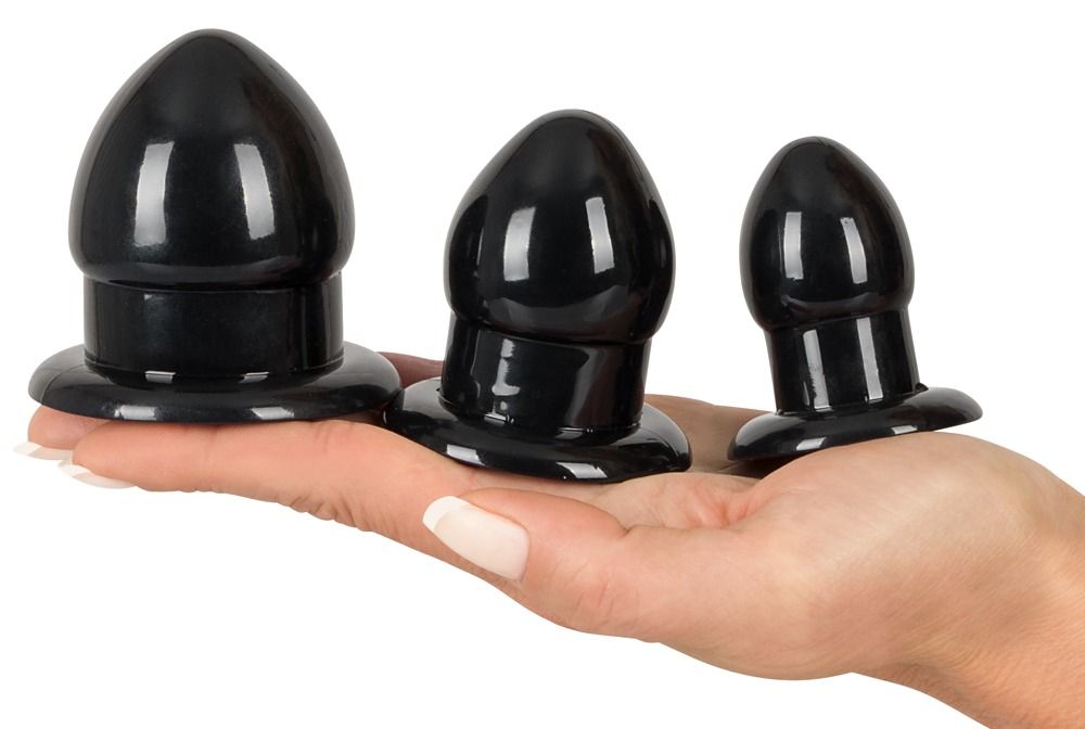 Main tenant trois plugs d'étirement anal noirs de tailles différentes.