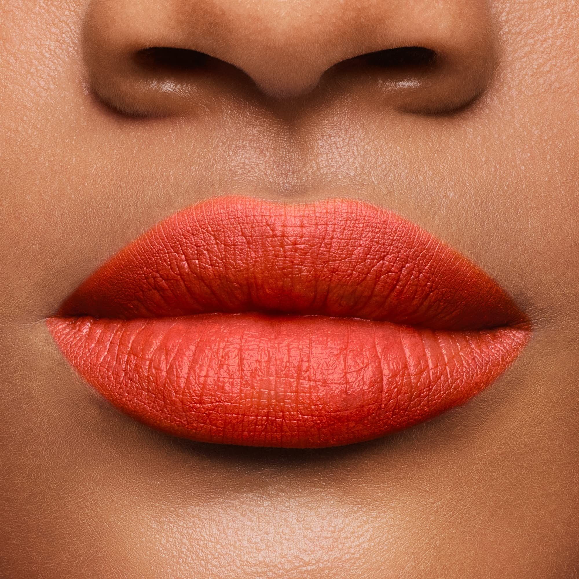 Gros plan sur des lèvres recouvertes de rouge à lèvres orange. Teint.