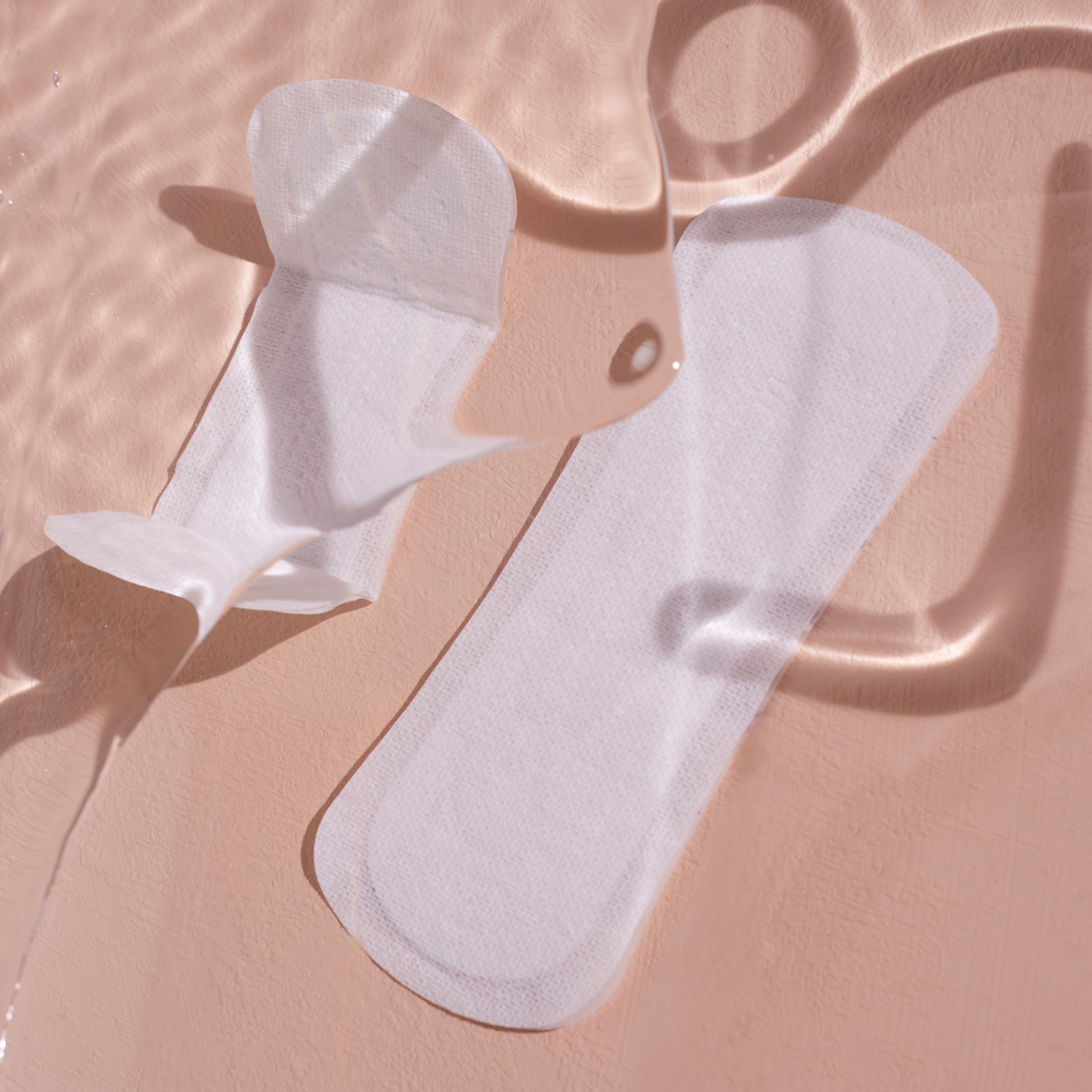 Deux protège-slips blancs sur surface rose. L'un est ouvert.
