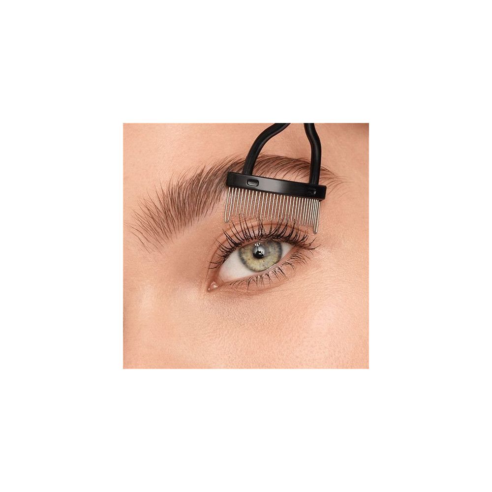 Gros plan sur un œil avec des cils. Une brosse séparatrice de cils est utilisée pour séparer les cils. Le produit est noir.