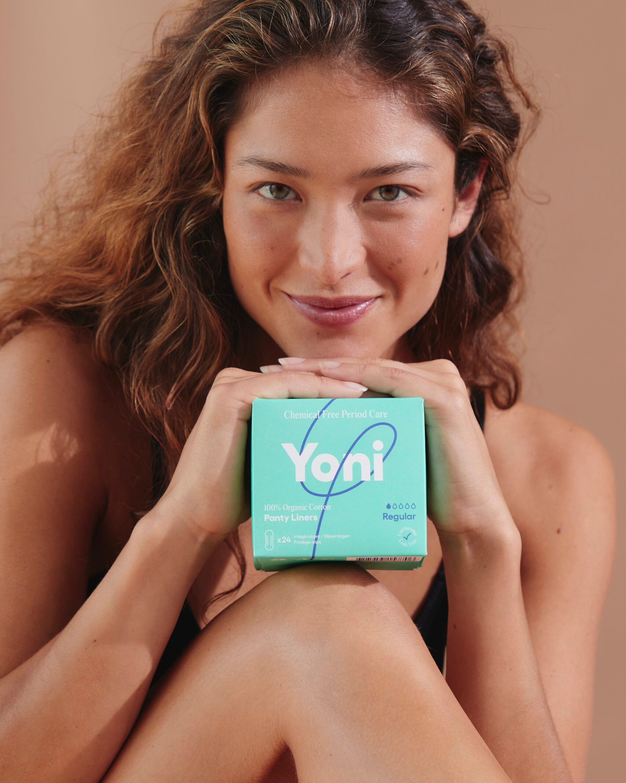 Femme tenant une boîte verte de protège-slips Yoni. Inscription : 100% coton bio. Régulier.