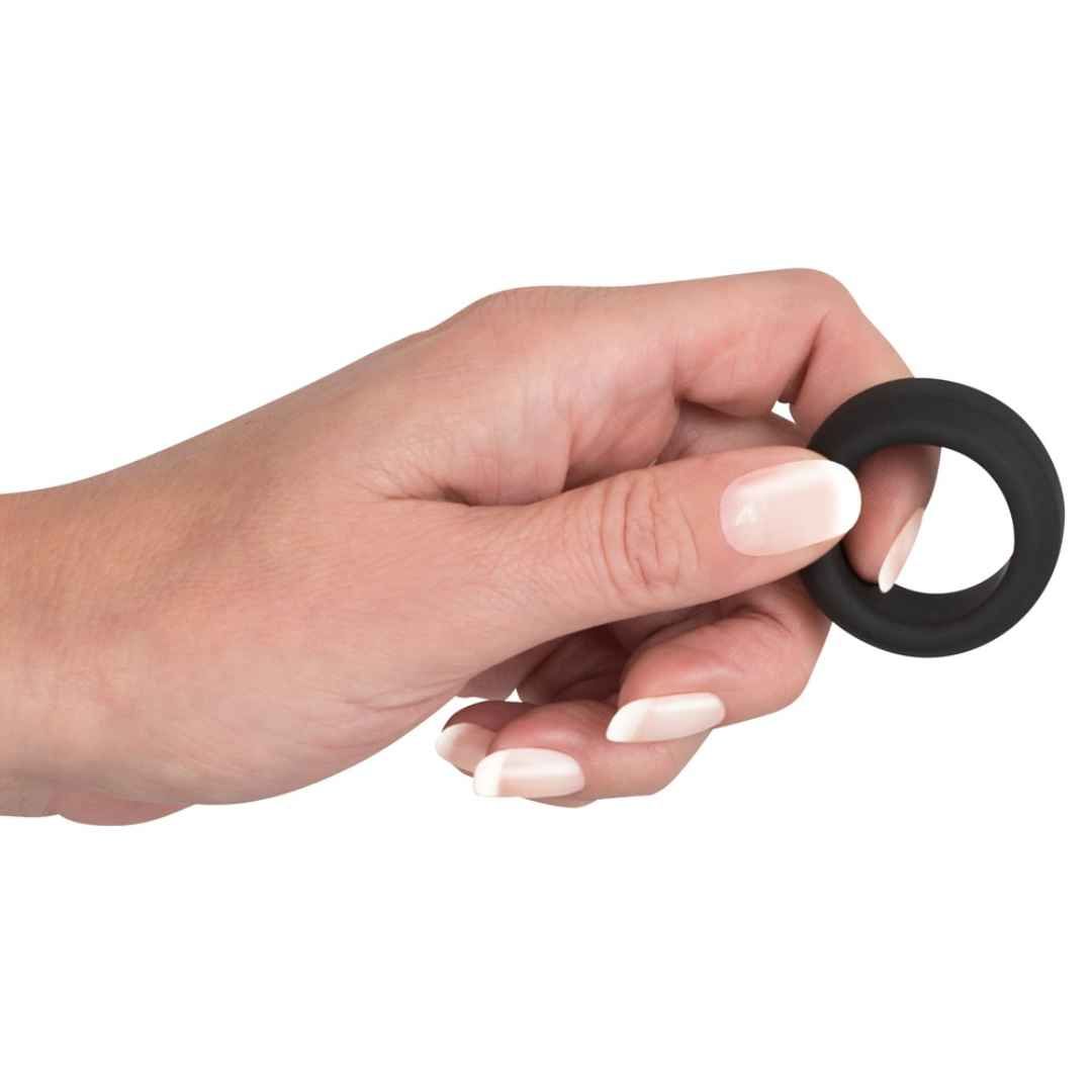 Main tenant une bague de pénis en silicone noir.