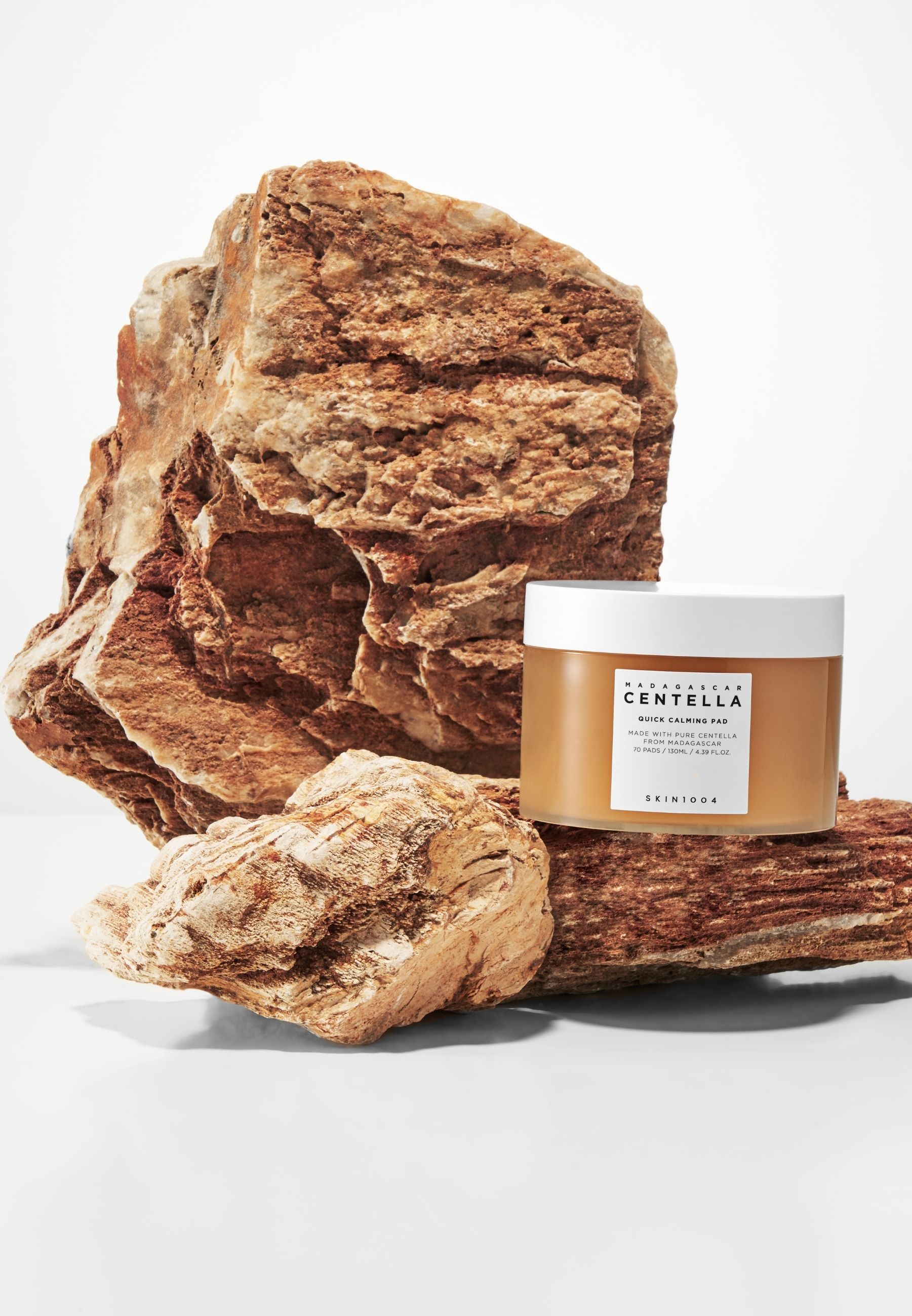 Pot met pads naast stenen. Label: MADAGASCAR CENTELLA, QUICK CALMING PAD, SKIN1004.
